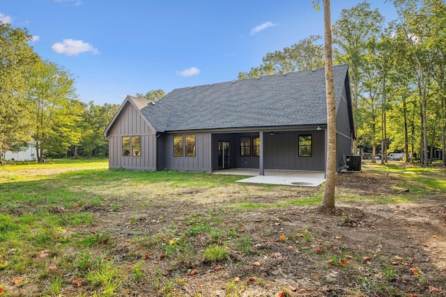 rear view of house featuring a shingled roof, cooling unit, board and batten siding, and a patio area