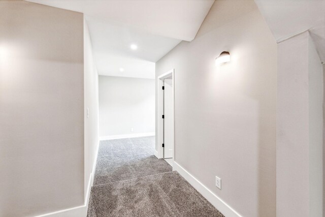 corridor featuring baseboards and carpet flooring