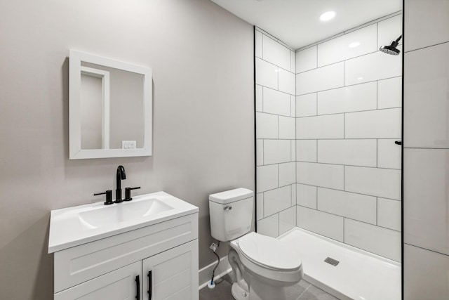 full bath featuring baseboards, a tile shower, toilet, and vanity
