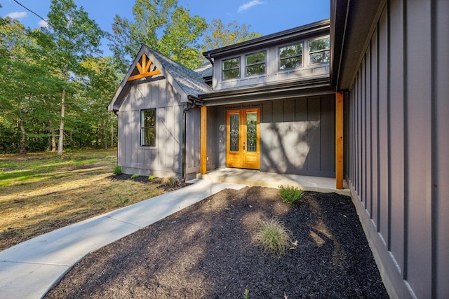 entrance to property featuring french doors and roof with shingles
