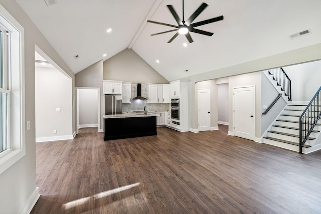 unfurnished living room with stairs, dark wood-style flooring, baseboards, visible vents, and ceiling fan