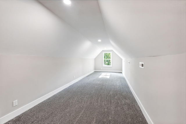 additional living space with carpet flooring, baseboards, vaulted ceiling, and visible vents