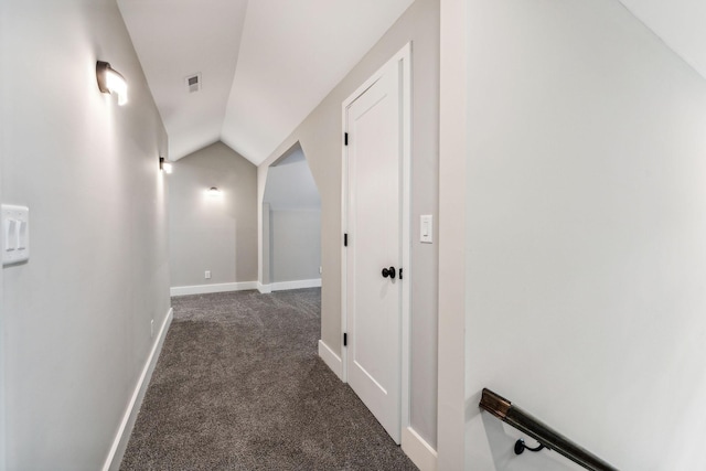 corridor featuring baseboards, dark carpet, vaulted ceiling, and visible vents