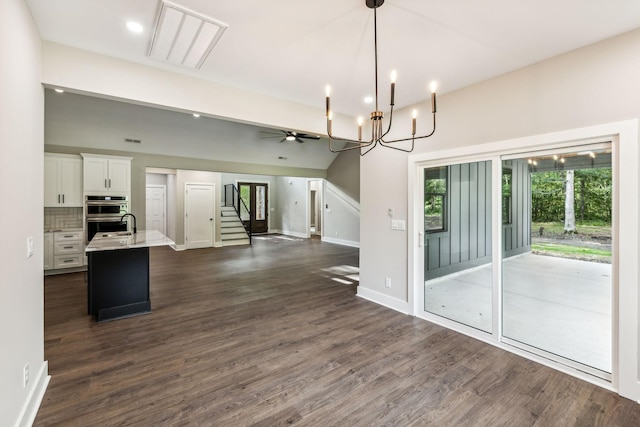 kitchen featuring light countertops, white cabinets, a kitchen island with sink, open floor plan, and dark wood-style floors