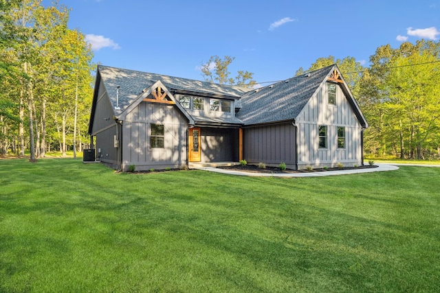 exterior space with board and batten siding, central AC, roof with shingles, and a lawn