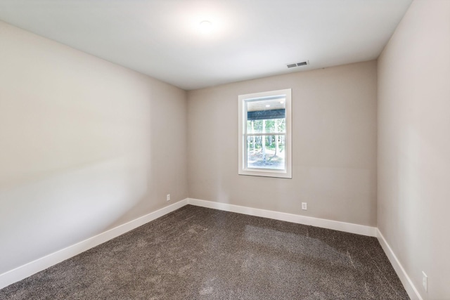 empty room with visible vents, baseboards, and dark carpet
