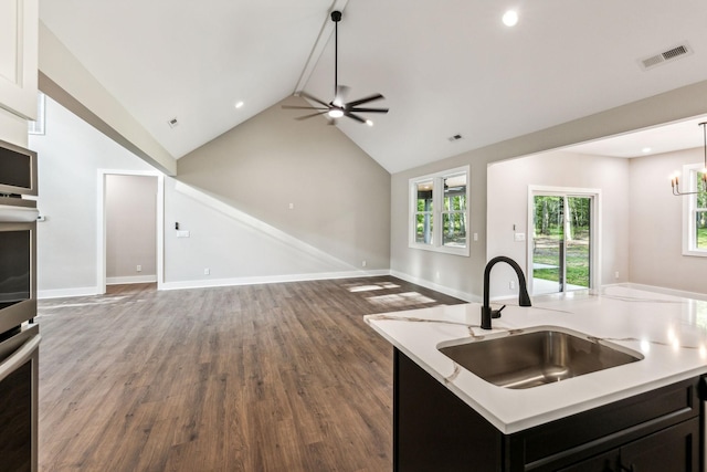 kitchen with a sink, open floor plan, lofted ceiling, ceiling fan with notable chandelier, and visible vents