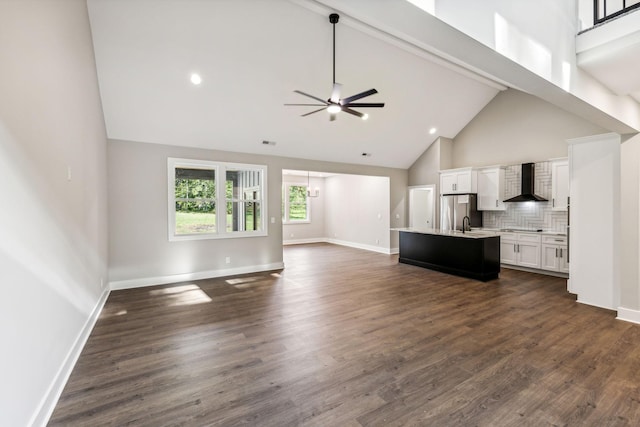 unfurnished living room with dark wood-style floors, high vaulted ceiling, baseboards, and a ceiling fan