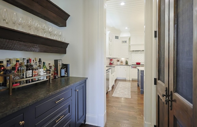 bar with a bar, dishwasher, backsplash, dark wood-style floors, and recessed lighting