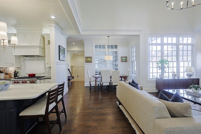living area featuring baseboards, recessed lighting, a chandelier, crown molding, and dark wood-type flooring