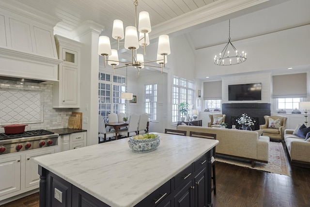 kitchen featuring stainless steel gas stovetop, backsplash, white cabinets, and a notable chandelier