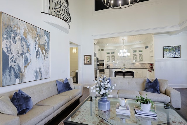 living area featuring baseboards, wood finished floors, a chandelier, and ornamental molding