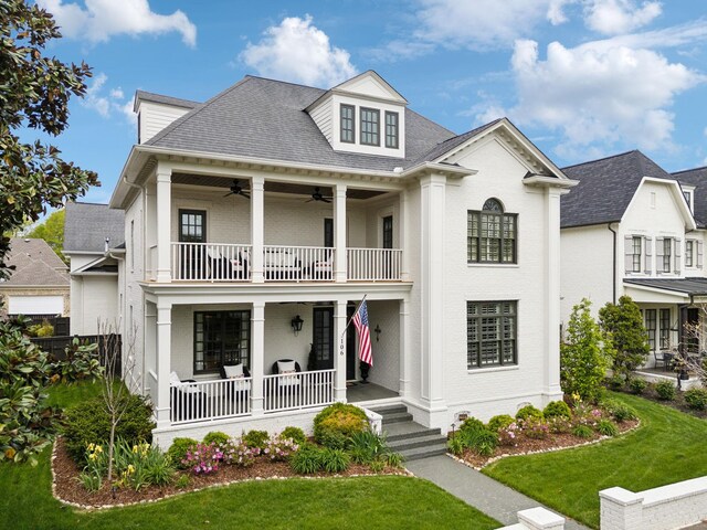 greek revival inspired property featuring covered porch, a ceiling fan, a balcony, and a front yard