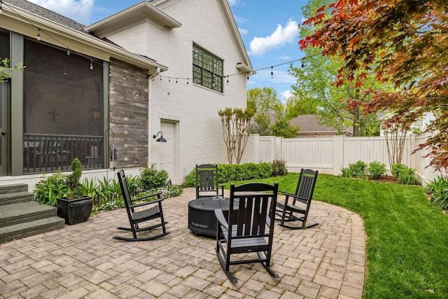 view of patio / terrace with a fire pit, a sunroom, and fence private yard