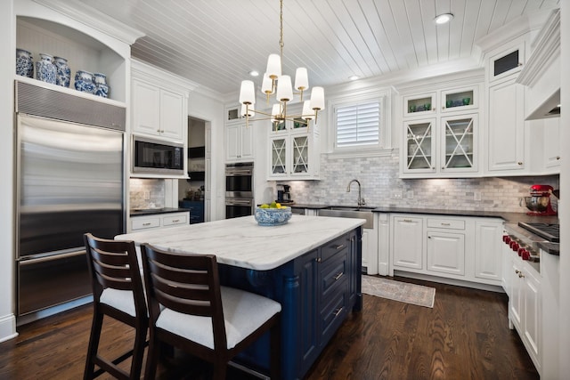 kitchen with built in appliances, white cabinetry, and a chandelier
