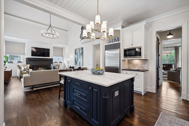kitchen with built in appliances, lofted ceiling with beams, white cabinetry, and a chandelier