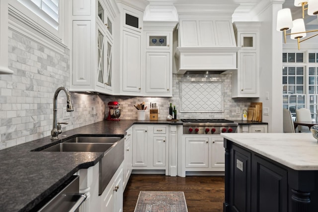 kitchen featuring tasteful backsplash, stainless steel gas stovetop, an inviting chandelier, custom range hood, and white cabinets