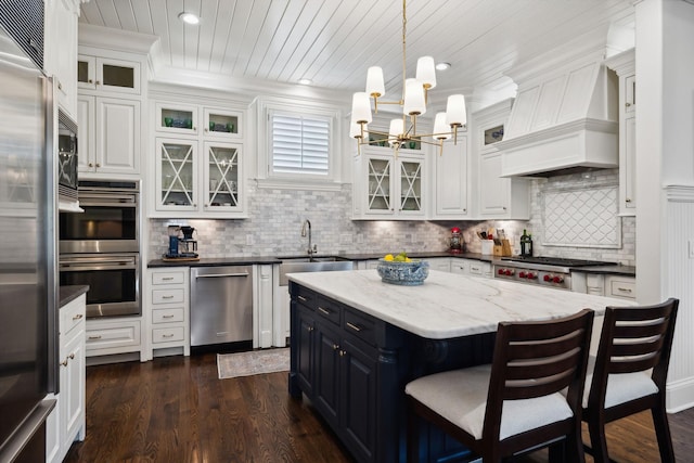 kitchen featuring stainless steel appliances, a sink, a chandelier, wood ceiling, and a breakfast bar area