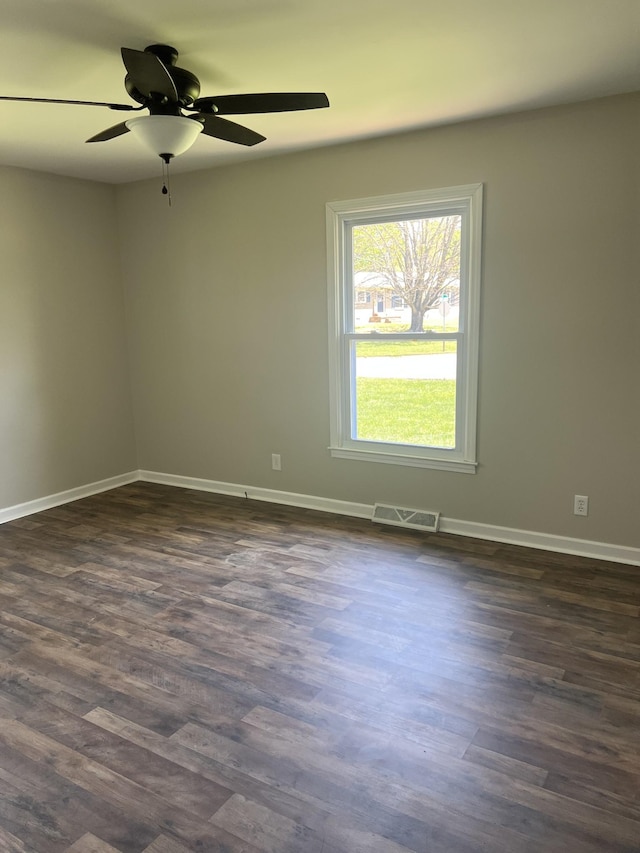 empty room featuring dark wood-type flooring, baseboards, a ceiling fan, and visible vents