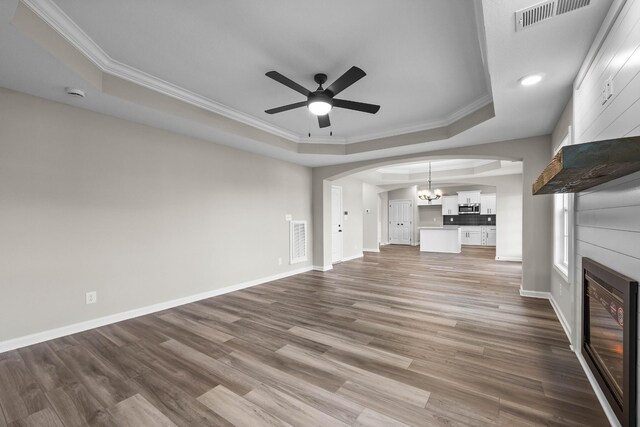 2539 Rafiki Dr, Clarksville, TN 37042 - unfurnished living room featuring a tray ceiling, arched walkways, a chandelier, a ceiling fan, and ornamental molding