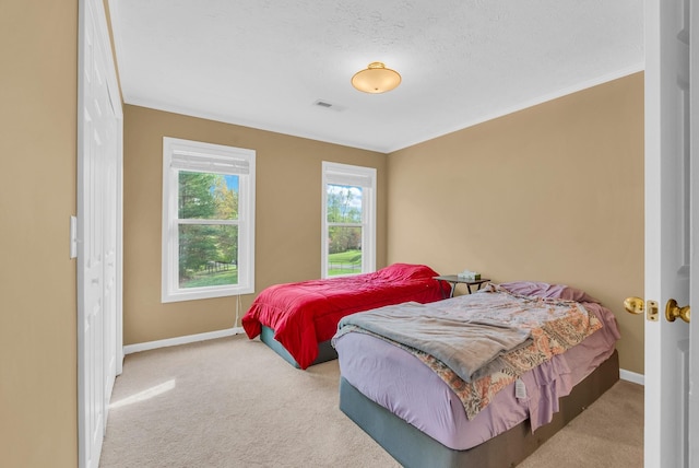 bedroom featuring baseboards, crown molding, visible vents, and carpet floors