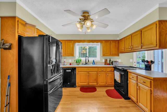 kitchen featuring a peninsula, a sink, a textured ceiling, black appliances, and light wood-style floors