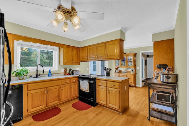 kitchen with light wood-style flooring, ceiling fan, a sink, a peninsula, and black appliances
