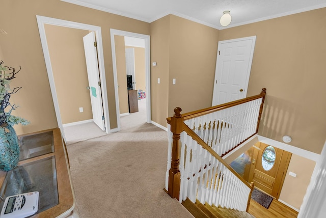 hallway with crown molding, carpet floors, baseboards, and an upstairs landing