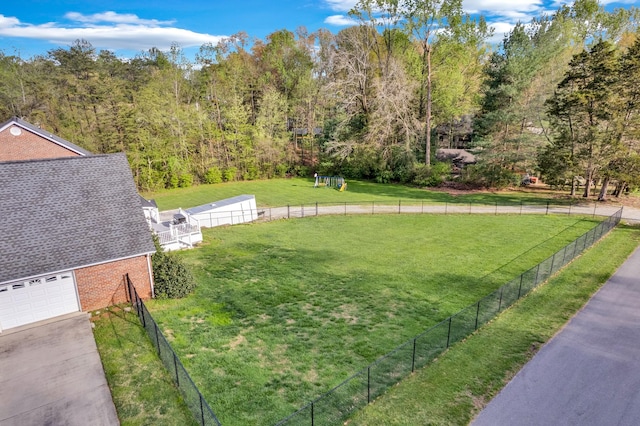 view of yard with driveway, a garage, and fence