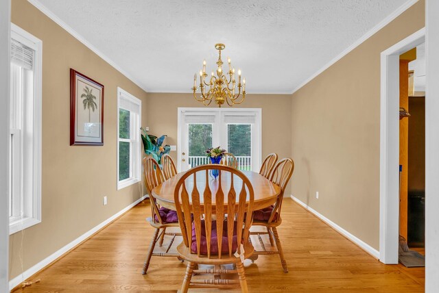 dining space with an inviting chandelier, light wood-type flooring, a textured ceiling, baseboards, and ornamental molding