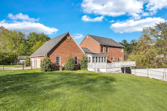 rear view of property featuring brick siding, a wooden deck, fence, and a lawn