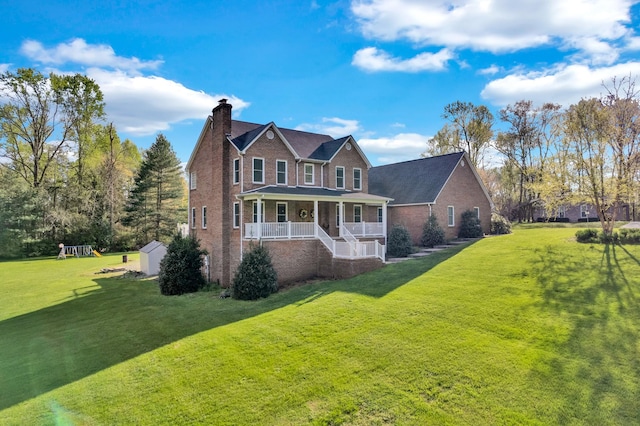 exterior space with covered porch, a chimney, a yard, and brick siding