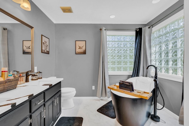 full bath featuring baseboards, toilet, visible vents, vanity, and a freestanding tub