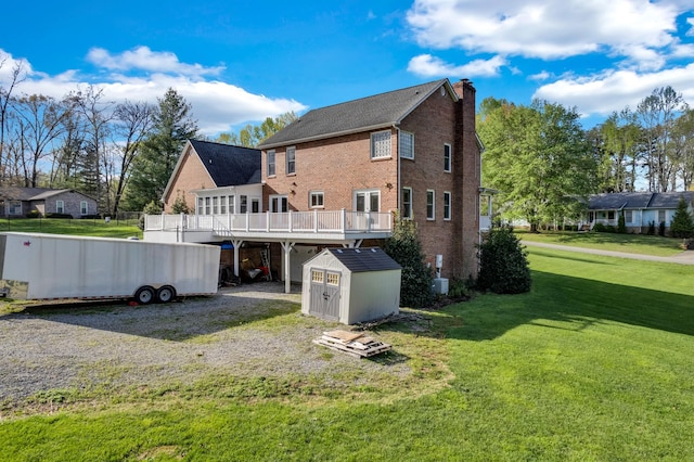 rear view of house with a storage shed, a chimney, a deck, a lawn, and an outbuilding
