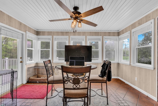 sunroom featuring wooden walls and a healthy amount of sunlight