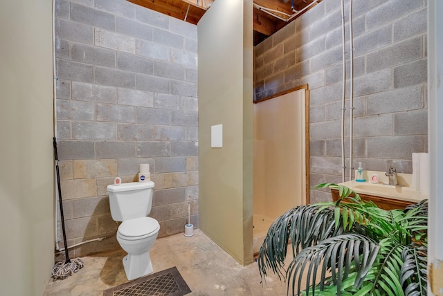 full bathroom featuring a sink, toilet, concrete flooring, a shower stall, and concrete block wall