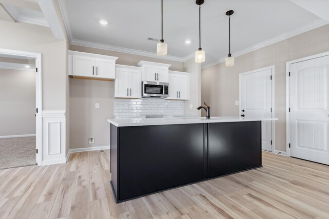 2531 Rafiki Dr, Clarksville, TN 37042 - kitchen featuring a sink, light wood-style flooring, stainless steel microwave, white cabinets, and decorative backsplash