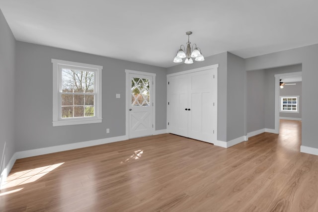 entrance foyer featuring baseboards, light wood-style flooring, and ceiling fan with notable chandelier
