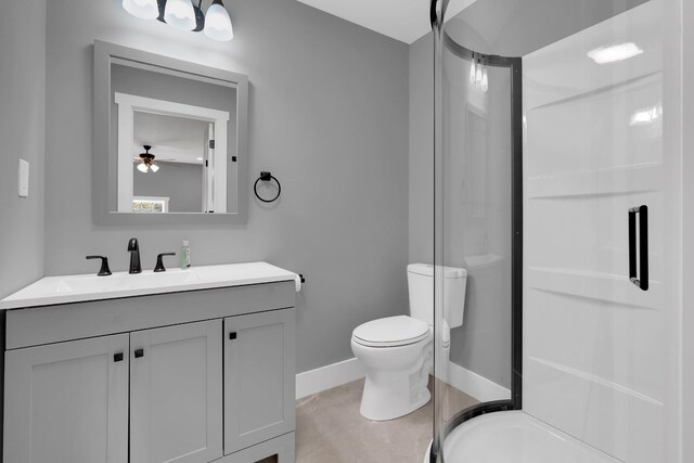 full bathroom featuring vanity, toilet, baseboards, a stall shower, and a ceiling fan