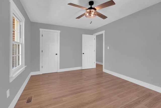 spare room featuring visible vents, baseboards, ceiling fan, light wood-type flooring, and a wealth of natural light