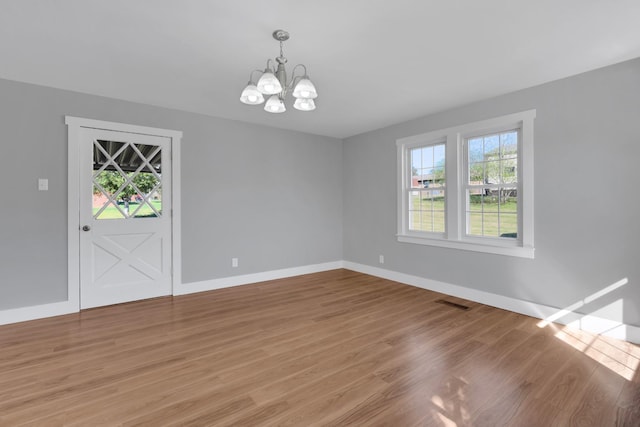 spare room with baseboards, visible vents, a chandelier, and light wood-type flooring