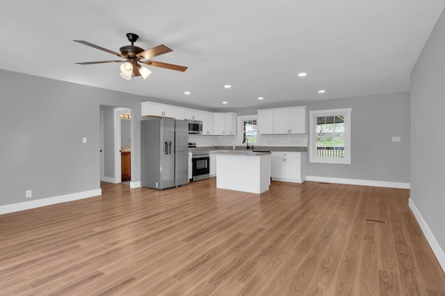 kitchen with open floor plan, backsplash, light wood-type flooring, and appliances with stainless steel finishes