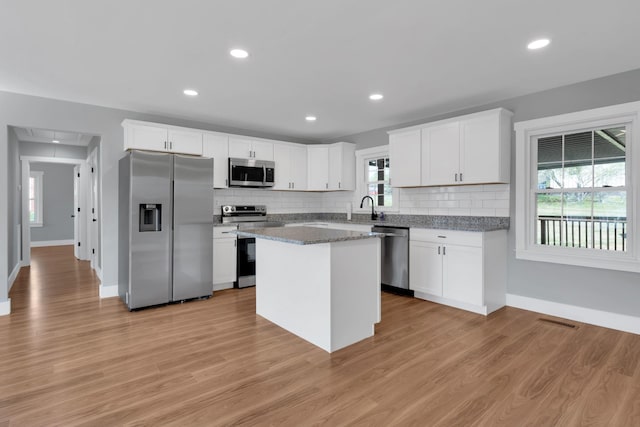 kitchen with decorative backsplash, a sink, light wood-style floors, and appliances with stainless steel finishes