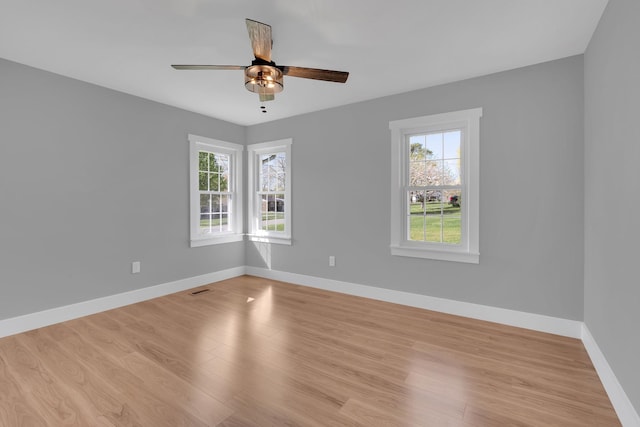 spare room with light wood finished floors, baseboards, visible vents, and ceiling fan