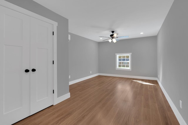 empty room featuring a ceiling fan, recessed lighting, baseboards, and wood finished floors