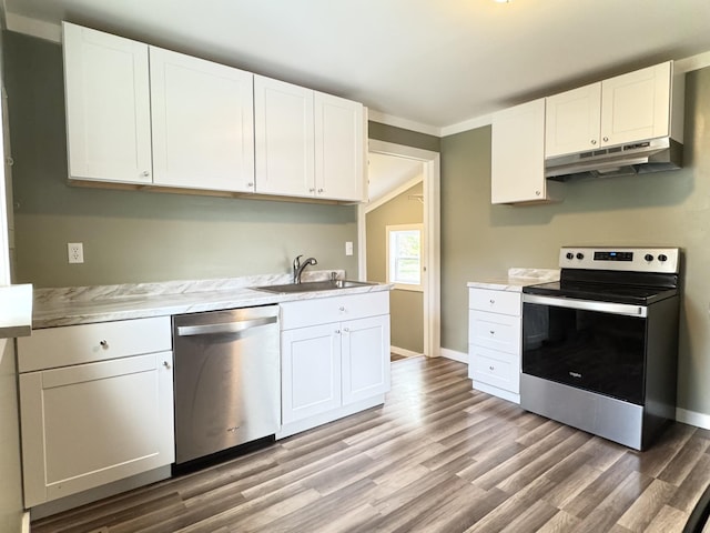 kitchen with white cabinetry, light countertops, stainless steel appliances, under cabinet range hood, and a sink