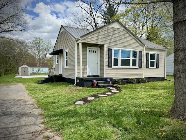 bungalow featuring metal roof, crawl space, a front lawn, an outdoor structure, and a shed