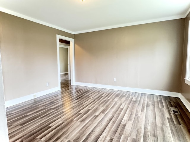 unfurnished room featuring visible vents, crown molding, baseboards, and wood finished floors