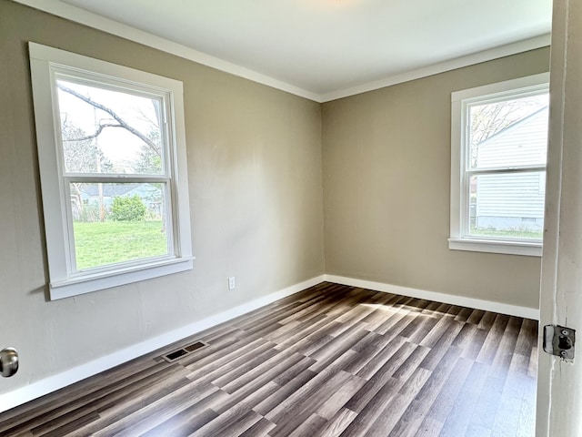 spare room with dark wood finished floors, baseboards, visible vents, and crown molding