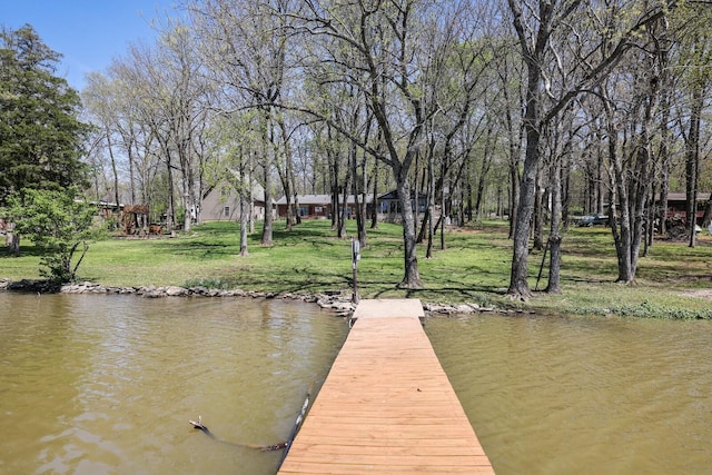 view of dock with a water view and a lawn